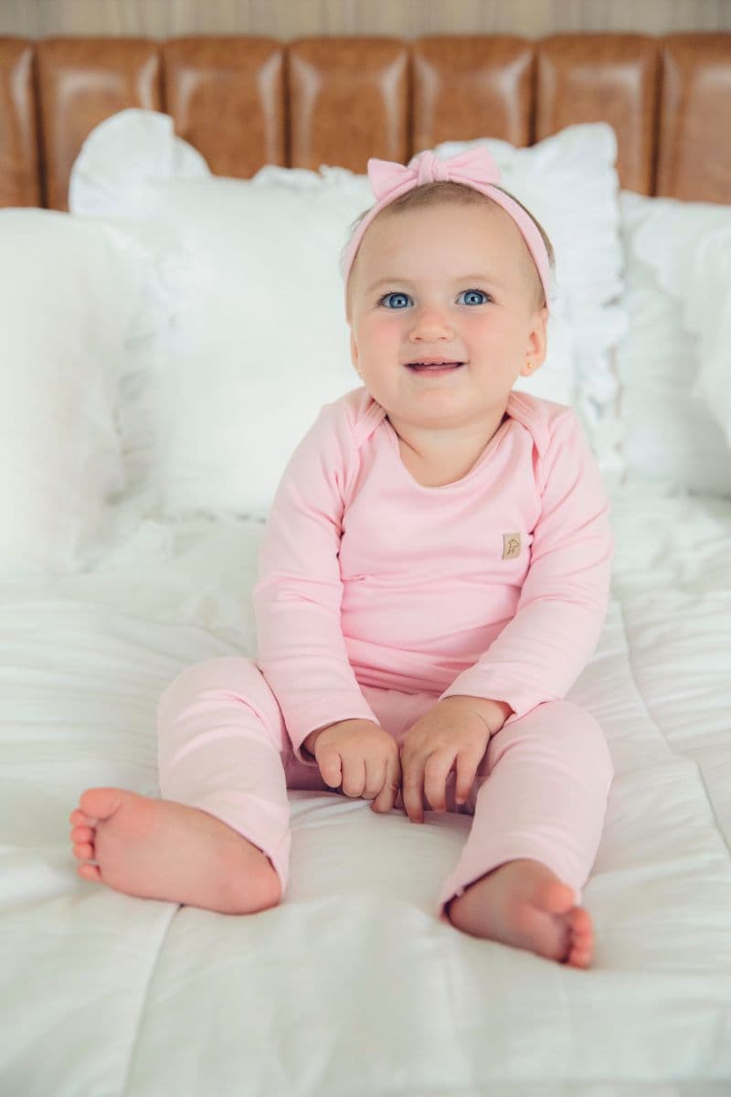 Bebê sentado vestindo o conjunto body e calça rosa bebê da Welpie